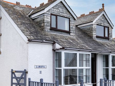 Exterior of a white house with two dormer windows and a grey tiled roof at Lamorna in Port Isaac