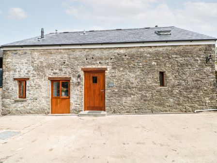 A stone building with wooden doors and windows at Lime Kiln Cottage in Cowbridge