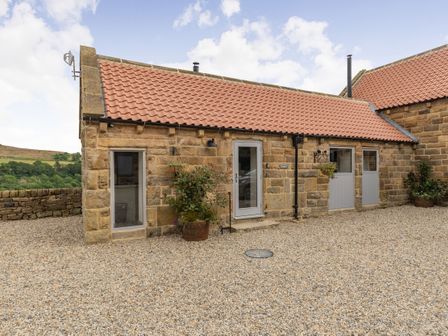 A stone building with three doors and two windows surrounded by gravel at Foxglove in Goathland