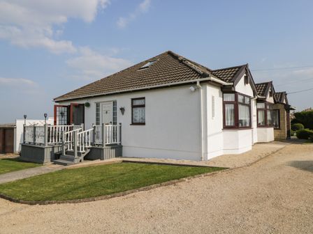 A single story house with a tiled roof a wooden deck and lawn at Annex Chetnole in Dundry