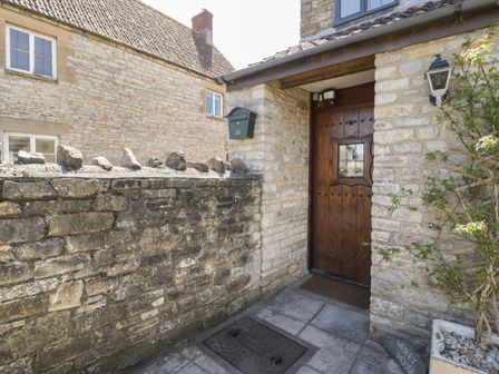 A stone house entrance with a wooden door and a stone wall at Wesley House in Pilton