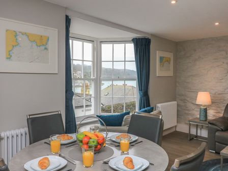 A dining table with croissants and glasses of orange juice in a living room with a window showing a view at Queens View in Dartmouth