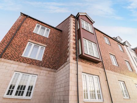 The exterior of a multi-story building with brick and stone walls and multiple windows at Abbey View in Whitby