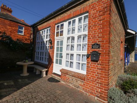 A brick house exterior with white framed windows a door a mailbox and a small outdoor table with a bench at Goliath in Brewers Quay Harbour