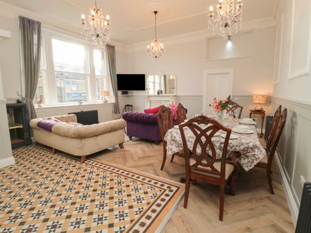 A living room with a dining table and chairs a beige sofa and a purple sofa under windows at The Vault House in Bellingham