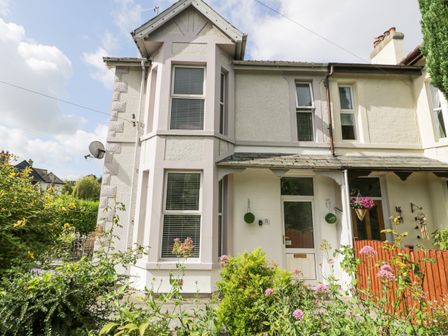 A two-story house with bay windows and a garden in front at 24 Cadnant Park in Conwy