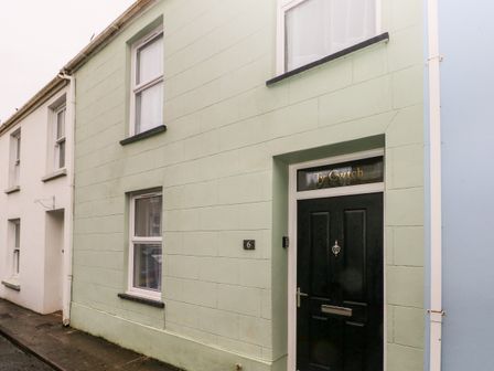 Exterior of a house with a black door and windows on a street at Ty Cwtch in Tenby