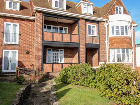 Exterior view of a brick building with balconies windows and surrounding garden at Ocean Watch 5 in Greenhill