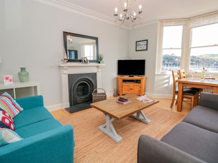 A living room with sofas fireplace coffee table and dining table by a window at River View in Dartmouth