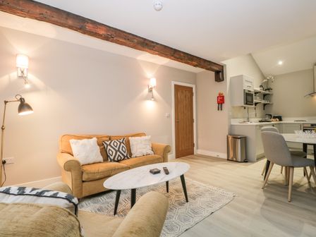 A living area with a sofa and coffee table next to a small kitchen with dining table and chairs at Windermere in Kendal