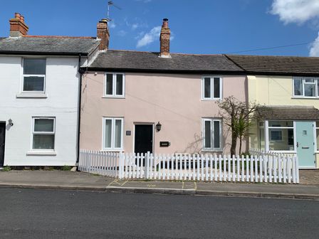 A row of houses with a white picket fence and small garden in front at Smugglers Cottage in Christchurch