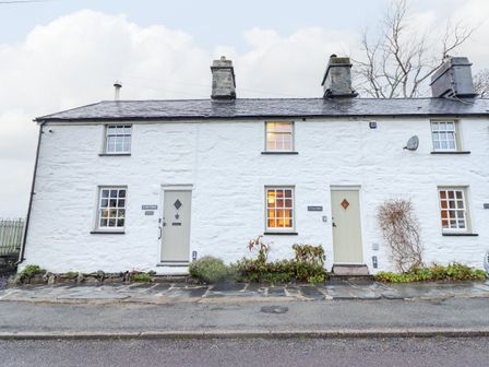 A white stone terrace house with two doors and windows along a street at Bwthyn Y Bugail in Manod near Blaenau Ffestiniog