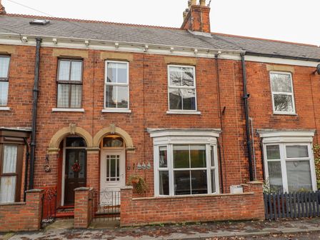 A row of brick terraced houses with arched doorways and windows at Coastguard Cottages in East Riding