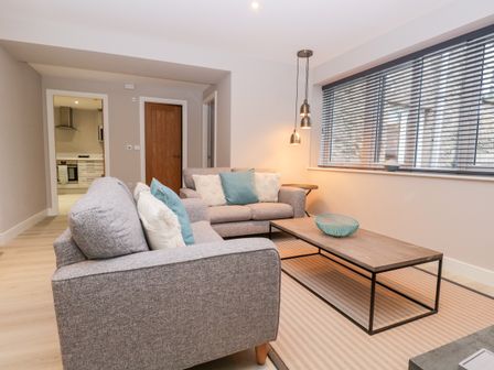 A living room with two grey sofas blue and white cushions a wooden coffee table and window blinds at Grizedale in Kendal