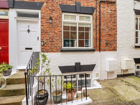 Front entrance with white door number 2 and potted plants on the steps at Anchor Cottage in Whitby