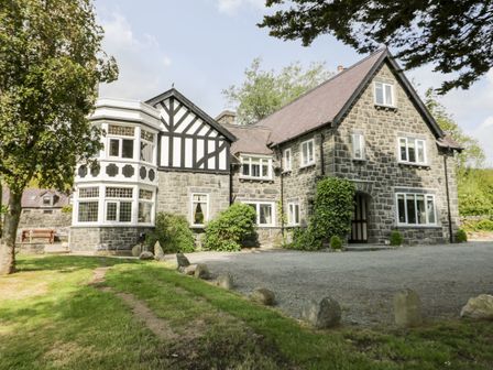 A stone and timber house with multiple windows and a gravel driveway at Gwern Borter Manor in Conwy