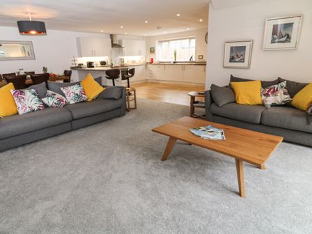 A living room with two grey sofas, a wooden coffee table, and an open kitchen in Brewers Cottage in Looe
