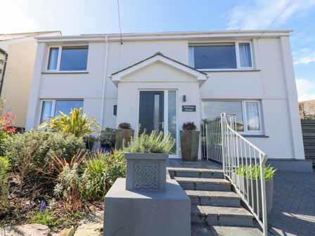 Exterior view of a two story house with a front entrance door stairs and plants at Pickney House Killigarth near Polperro