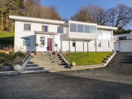 Exterior view of a white two-story house with stone steps leading to a front door and a driveway at Brantlea in Bowness-On-Windermere