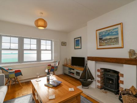 A living room with a wooden coffee table two patchwork chairs a fireplace and a window with an ocean view at Beach Retreat in Weymouth