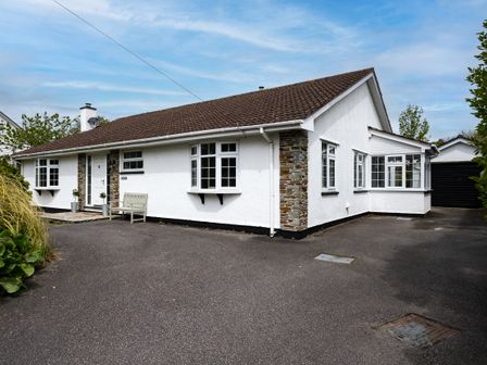 A detached house with white walls and a brown roof with a paved driveway at Samphire in Rock