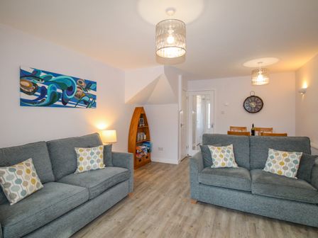 A living room with two grey sofas and a wooden boat-shaped shelf with books at Chesil Retreat Weymouth