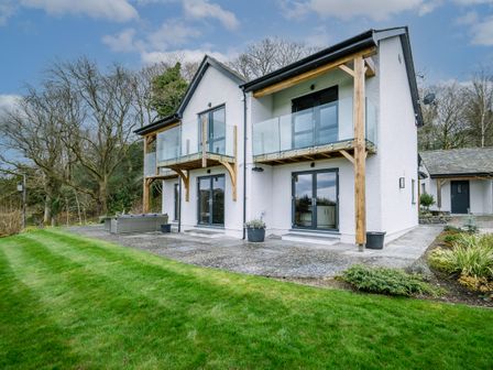 A two story house with balconies and glass railings overlooking a lawn at Cleabarrow View in Cleabarrow near Windermere
