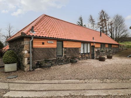 A stone and wood building with a tiled roof and potted plants outside at The Bakery in Middleton near Belford
