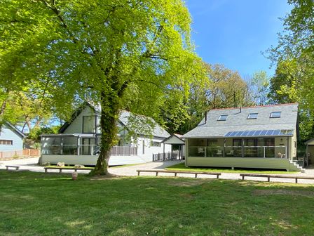 Two houses with large windows and a porch near trees and grass at Primrose in Hellandbridge near Bodmin