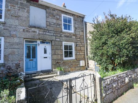 A stone house with a white door and a blue door separated by a small gravel front yard and a black metal gate at 6 Bellair Road Madron near Penzance