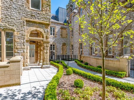 An outdoor courtyard with stone walls plants and a paved walkway at Rowley House at Stone Cross Mansion in Ulverston