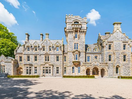 A large stone mansion with multiple windows and towers under a blue sky at The Margaret Suite Stone Cross Mansion in Ulverston