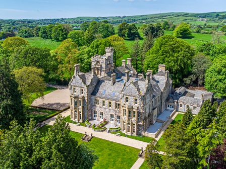 A large stone mansion surrounded by trees and green fields at The Lucy Suite Stone Cross Mansion in Ulverston