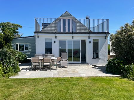 A backyard patio with outdoor dining furniture and sliding glass doors at Alpha in St Minver