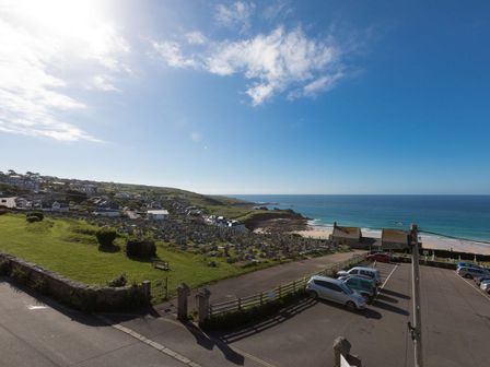 A coastal view with a cemetery, parking lot, beach, and houses in St Ives