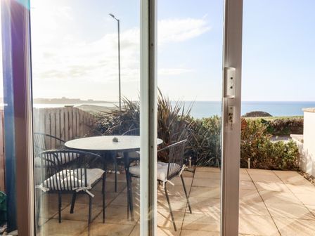 A patio with a round table and chairs overlooking the sea at Flat 2 in Porth near Newquay