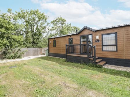 A mobile home with a deck surrounded by grass at Serendipity