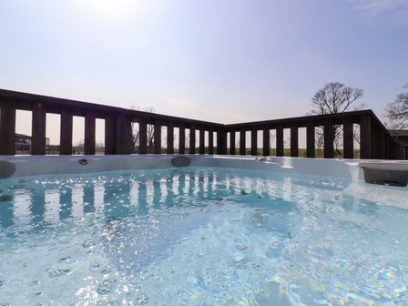 An outdoor jacuzzi with bubbling water and wooden railing around at Skylarks in Fornham St Genevieve near Bury St Edmunds