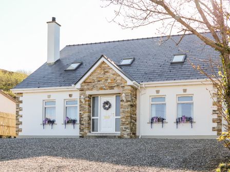 A house with a stone entrance and flower boxes under windows in Annagry County Donegal