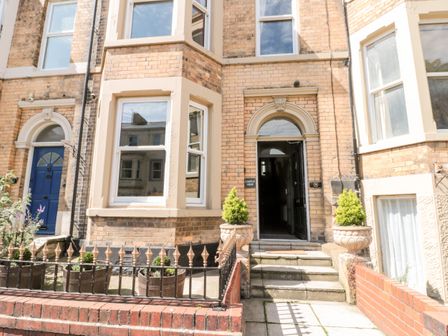 Entrance of a brick building with steps leading to a dark doorway and potted plants at Castle View in Scarborough