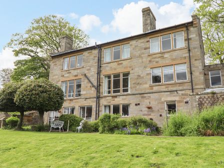 A stone building with multiple windows a lawn and garden furniture at The Garden Apartment in Aislaby