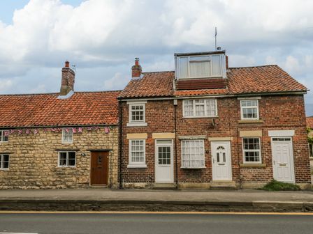 A row of brick and stone houses with tiled roofs and multiple doors and windows along a roadside at Duckys in Pickering