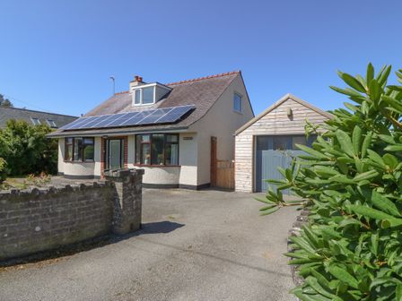 A detached house with solar panels on the roof and a wooden garage at Awelfryn in Elim near Llanddeusant