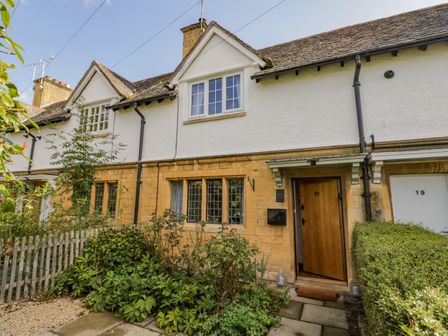 A row of terraced houses with stone and white exterior walls and wooden doors at Blossom Cottage in Broadway