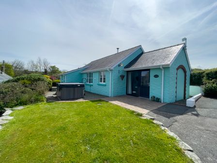 A stone house painted turquoise with a hot tub outside and a grassy yard at Ty Coed @ Canllefaes in Penparc near Cardigan
