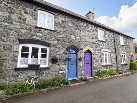 A stone cottage exterior with blue and purple doors and flower pots at Coed Y Glyn in Llanuwchllyn near Bala