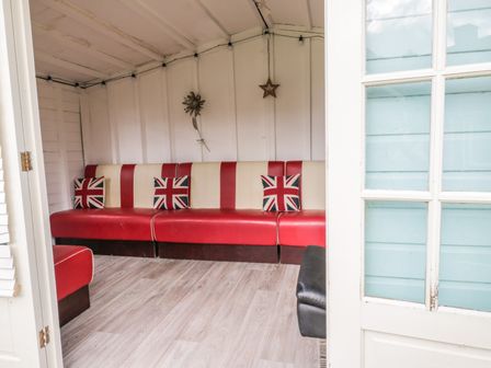 An indoor seating area with red and cream bench seating and Union Jack cushions at Wyvill House in Cayton