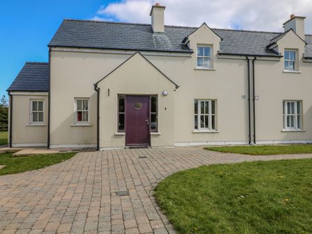 A two-story cream colored house with a dark purple door and paved walkway at CountryView in Ballinalira near Ring Dungarvan County Waterford
