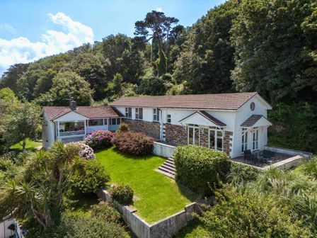 A house with a garden and patio surrounded by trees at Beach Haven in Polzeath