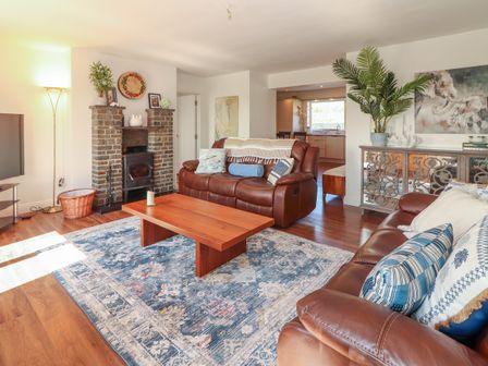 A living room with brown leather sofas a wooden coffee table a patterned rug and a brick fireplace at Cottage View in Moveen East near Kilkee County Clare